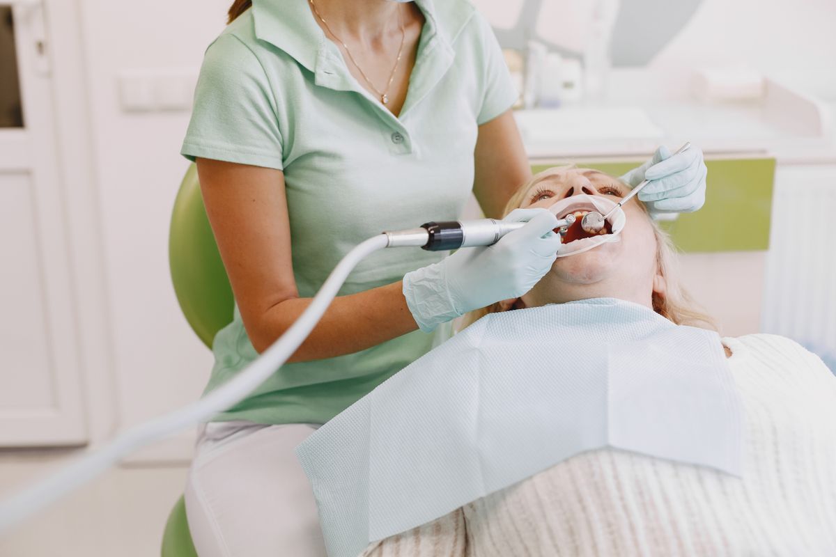 Seduta di igiene professionale su una paziente in poltrona odontoiatrica